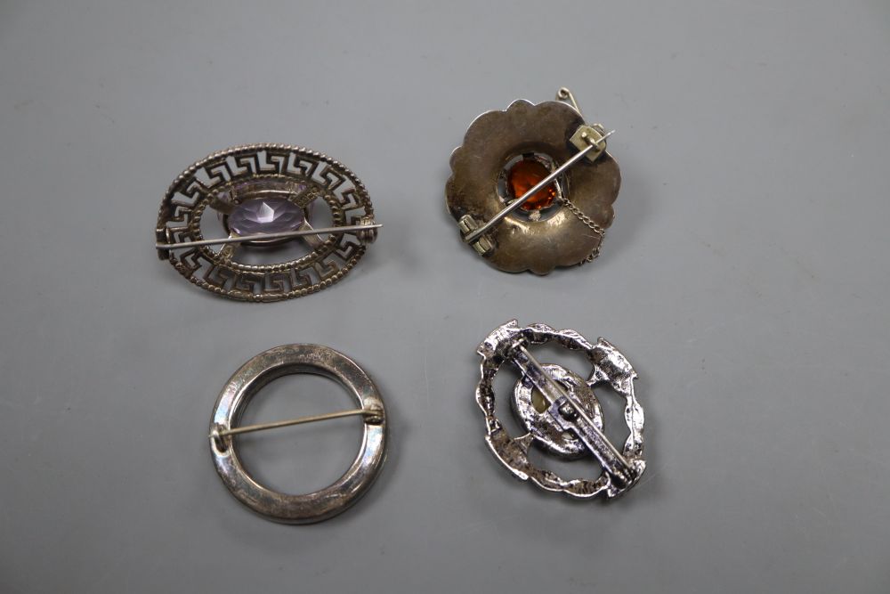 A Scottish pieced silver and amethyst set oval brooch, two white metal and Scottish hardstone brooches and one other brooch.